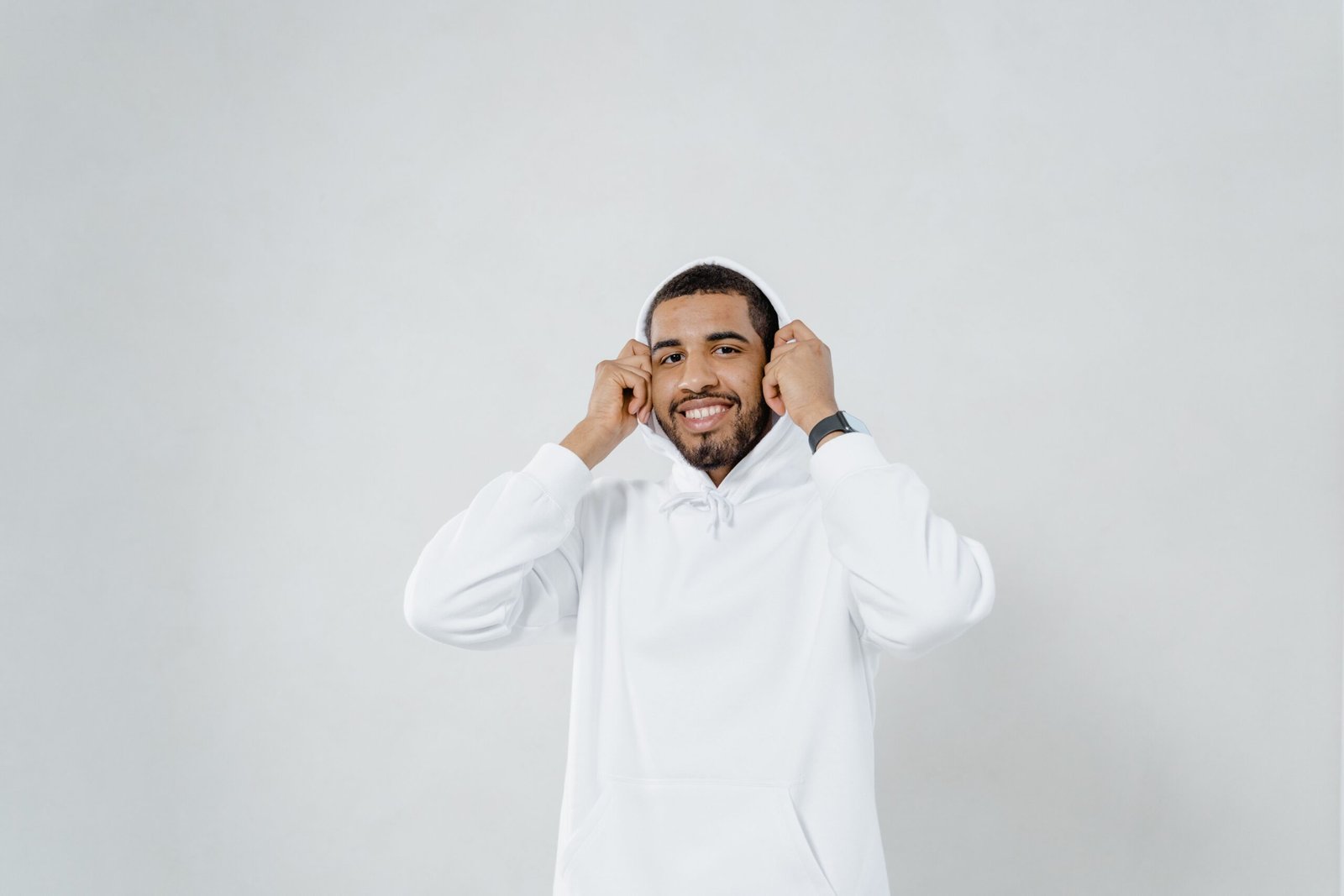 Smiling man with beard and mustache wearing a white hoodie in studio setting.